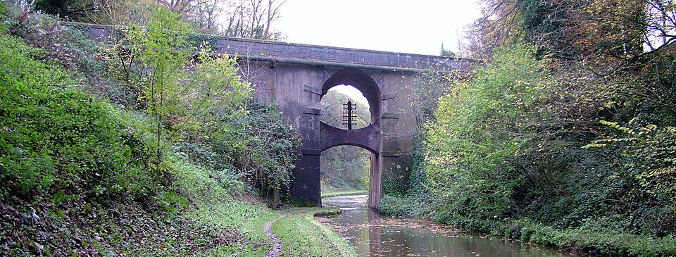 A high bridge over a narrow canal. Trees cling to the steep banks on either side.